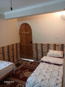 Maison authentique au cœur des oasis في غرداية: غرفة نوم بسريرين وباب فيها سجادة +5 صور
