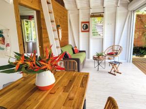 a porch with a wooden table with a vase of flowers at Au son des Grenouilles in Sainte-Rose