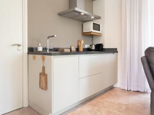 une cuisine avec des armoires blanches et un évier dans l'établissement Sfeervolle Studio - Privéterras & Vloerverkoeling - Achterhoek, à Almen 15 autres photos