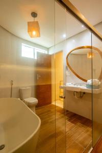 a bathroom with a tub and a toilet and a mirror at Baía Branca Beach Resort in Tamandaré