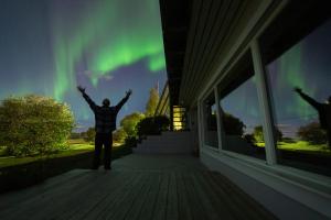 a man standing on a porch looking at the aurora at Northern Lights Apartment in Mortenhals