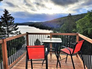 two chairs and a table on a deck overlooking a river at La Passion #204 - Loft with private balcony and view in Sainte-Lucie-de-Doncaster