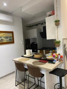 eine Küche mit einer Theke mit Stühlen und einem Tisch in der Unterkunft Appartement coquet à Hammamet in Hammamet