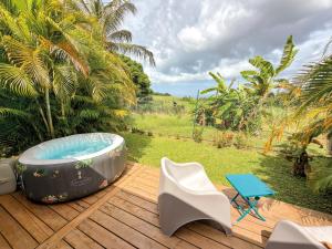 a hot tub sitting on a wooden deck with a chair at Au son des Grenouilles in Sainte-Rose