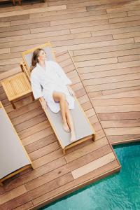 une femme assise sur une chaise près d'une piscine dans l'établissement Best Western Plus Le Roi Arthur Hôtel & Spa, à Ploërmel