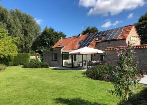 a house with a solar roof with a yard at De Kruishoeve in De Haan