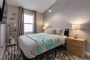 a bedroom with a bed with a night stand and a window at Casablanca - 3 BR Family & Game Haven in Calgary