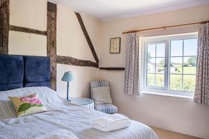 Cleaver Cottage في أندوفر: غرفة نوم بها سرير ونافذة وكرسي