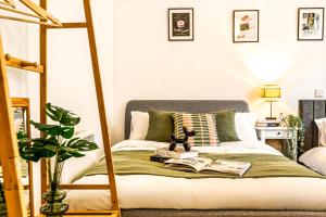 a bed with a green blanket and a book at The Viva Apartments Luxe in Birmingham