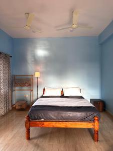 a bedroom with a bed with a blue wall at Barefoot and Beyond - Crafted with Kenchas in Gokarna