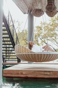 a woman laying in a hammock on a dock at Best Western Plus Le Roi Arthur Hôtel & Spa in Ploërmel