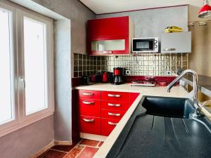 studio 2 personnes coeur de ville - proche plage في لي سابلِ دولونْ: مطبخ بخزائن حمراء ومغسلة +7 صور