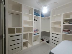 a white walk in closet with white shelves at Chácara Aricanga in Aracruz