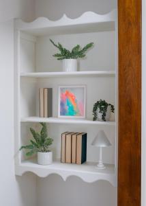 a white book shelf with books and potted plants at Classic American-style, 18 min to NYC in Carlstadt