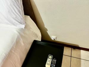 un letto con un telecomando accanto a un letto di Feel At Home Cosy Apartment a Gaborone
