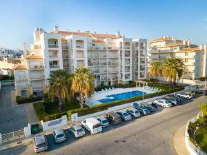 an apartment complex with cars parked in a parking lot at Ver o Mar in Albufeira