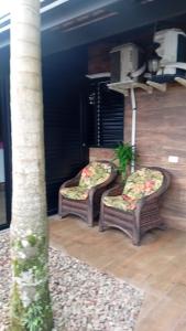 two wicker chairs sitting on top of a porch at Cantinho das Palmeiras em Itapoá- Casa c piscina p 6 pessoas in Itapoa