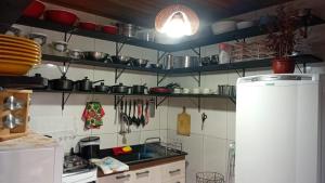 a kitchen with many pots and pans on the wall at Cantinho das Palmeiras em Itapoá- Casa c piscina p 6 pessoas in Itapoa +13 photos