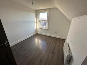 an empty living room with a window and wooden floors at Smart 2 bed apartment in Purley