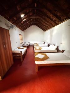 a row of beds in a room with red floors at Rafters Retreat Coorg The Riverside Homestay in Srimangala