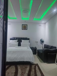 ein Schlafzimmer mit einem Bett und einem Sofa und grüner Beleuchtung in der Unterkunft Dups Guest House, in Pietermaritzburg