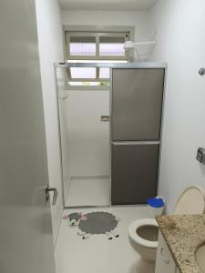 a bathroom with a toilet and a door with a poodle on the floor at Cantinho do Sossego in Campo Alegre