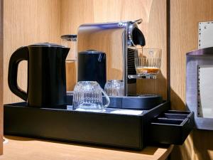 a coffee maker and glasses on a black tray at Novotel Paris Centre Bercy in Paris