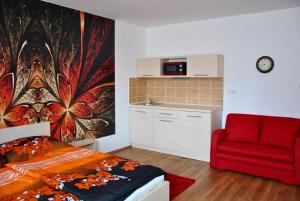 a bedroom with a bed and a red chair at Gyula Vár Prémium Apartman in Gyula