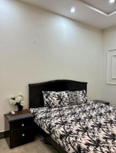 a bedroom with a black and white bed and a nightstand at 1 - bedroom near Lyallpur galleria in Faisalabad
