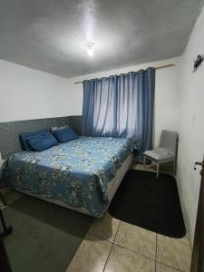 a bedroom with a bed with blue sheets and a chair at AP do Vale em Blumenau in Blumenau