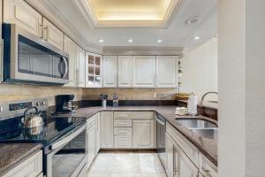 a kitchen with white cabinets and black counter tops at Mountainwood 303 in Breckenridge