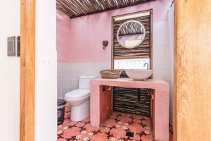a pink bathroom with a toilet and a mirror at Mar Amar Casa de Playa in Coveñas
