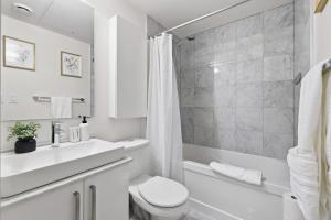 a white bathroom with a toilet and a sink at Stylish Downtown Studio with CN Tower Views in Toronto