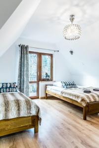 2 bedden in een witte kamer met een kroonluchter bij Willa u Baranów 2 in Zakopane +41 foto's