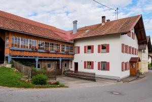 韦尔塔赫Am Dorfbrunnen - zentral in Wertach, authentisch, echt Allgäuerisch的一座大型白色建筑，有着红色的窗户和红色的屋顶。