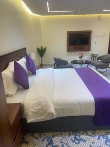 un grand lit avec des oreillers violets dans une chambre dans l'établissement سفانة هلا للشقق المخدومة, à Hafr Al Baten