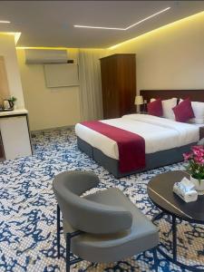 une chambre d'hôtel avec un grand lit et une chaise dans l'établissement سفانة هلا للشقق المخدومة, à Hafr Al Baten
