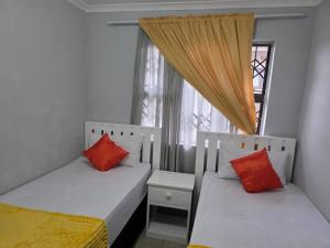 two beds with red pillows in a room with a window at Ngwanase Properties in Vosburg