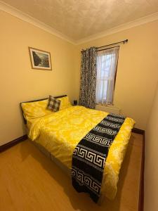 a bedroom with a bed with a yellow comforter and a window at Double & Single rooms in Southall in Southall