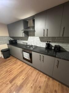 a kitchen with gray cabinets and a wooden floor at Double & Single rooms in Southall in Southall +7 photos