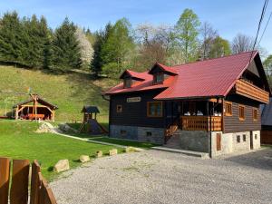 uma cabana de madeira com telhado vermelho e um playground em VILLA MARTINI em Lazy pod Makytou