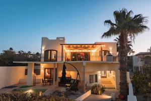 a large white house with a palm tree at Casa Reyes -All in One, Heated Pool & Beach Access in El Pueblito