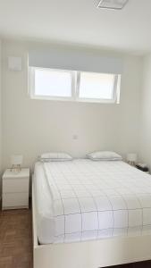 ein weißes Bett in einem weißen Zimmer mit zwei Fenstern in der Unterkunft Arm Apart in Brüssel
