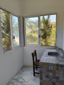 Zimmer mit 3 Fenstern, einem Tisch und einem Stuhl in der Unterkunft Fiesta Zipolite in Zipolite