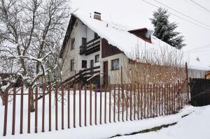 Una cerca frente a una casa con nieve. en Robotnícka ubytovňa Bodice 104, en Liptovský Mikuláš
