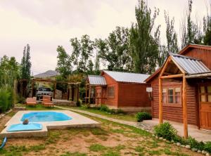 eine Blockhütte mit einem Pool im Hof in der Unterkunft Cabañas Rowal Malbec Potrerillos in Potrerillos