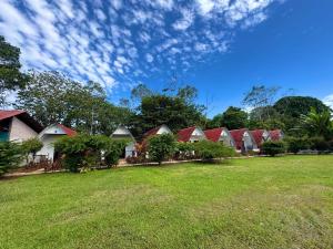 a row of houses with red roofs on a grass field at Eco Hotel Villas del Tortuguero in Cariari