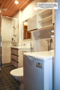 Un baño con inodoro, lavabo y frigorífico. en Syötteentupa, en Syöte