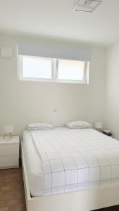 ein weißes Bett in einem weißen Zimmer mit zwei Fenstern in der Unterkunft Arm Apart in Brüssel + 22 Fotos