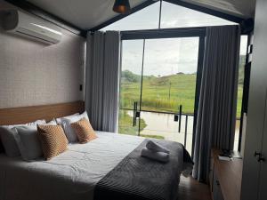 une chambre avec un lit et une grande fenêtre dans l'établissement Monakó Cabanas, à Bragança Paulista